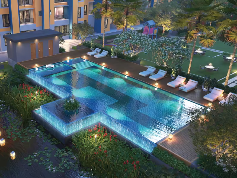 Infinity pool and kids' pool lit at night with deck loungers